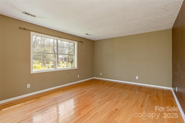 spare room with baseboards, visible vents, and light wood-style floors