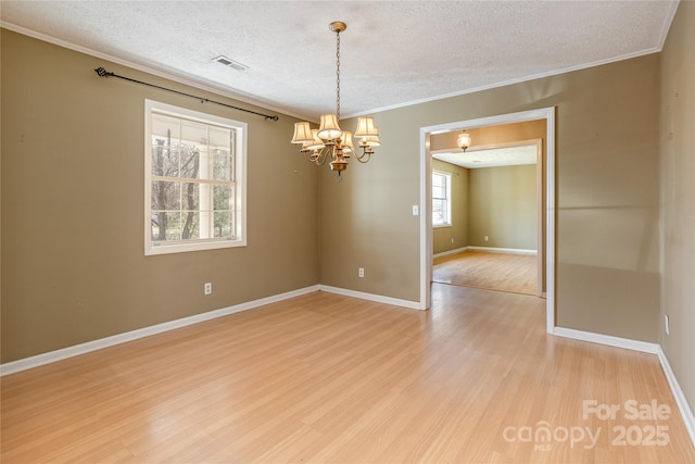 spare room featuring ornamental molding, visible vents, a notable chandelier, and light wood finished floors