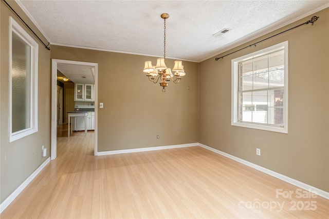 spare room featuring light wood-style flooring, a textured ceiling, visible vents, and a notable chandelier