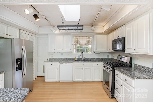 kitchen featuring white cabinets, light wood finished floors, stainless steel appliances, and a sink