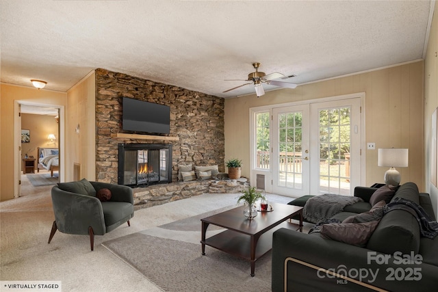 living room with ceiling fan, a textured ceiling, french doors, carpet floors, and a fireplace