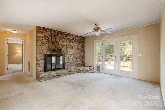 unfurnished living room featuring french doors, a textured ceiling, and a stone fireplace