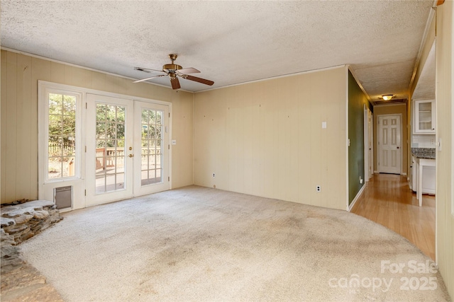 carpeted empty room featuring a textured ceiling, a ceiling fan, and french doors