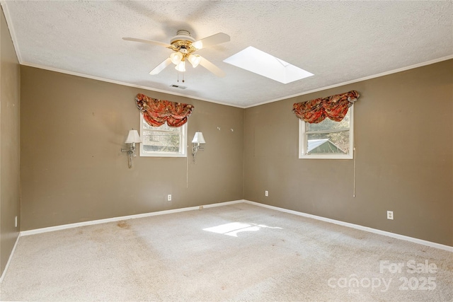 spare room with a textured ceiling, a skylight, carpet flooring, and baseboards