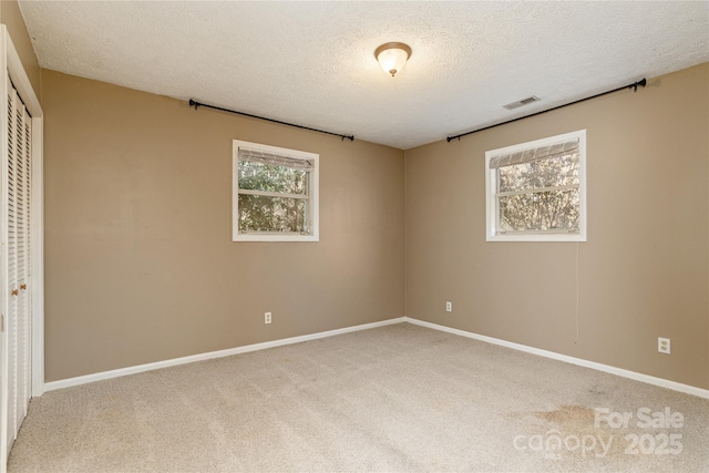 unfurnished bedroom with carpet floors, multiple windows, a closet, and visible vents