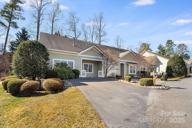 view of front of property featuring driveway, a shingled roof, and a front lawn