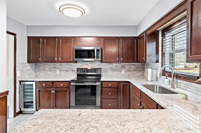 kitchen with stainless steel appliances, sink, backsplash, light stone counters, and beverage cooler