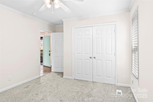 unfurnished bedroom with ceiling fan, ornamental molding, carpet flooring, and a closet