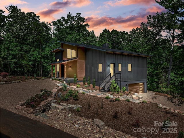 view of front of house with stairs, an attached garage, and driveway