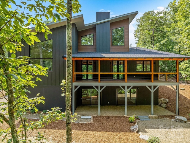 back of house featuring a patio, a chimney, and board and batten siding