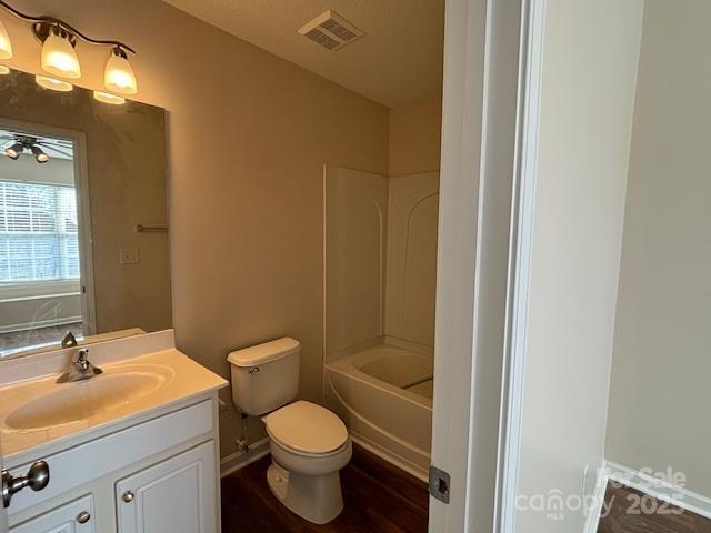 full bathroom featuring hardwood / wood-style floors, toilet, shower / bathing tub combination, and vanity