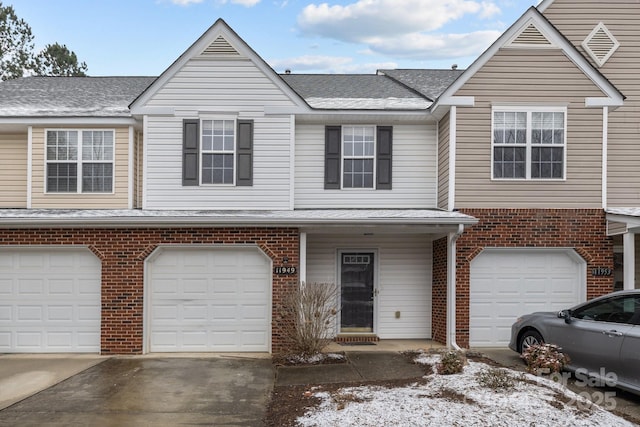 multi unit property featuring driveway, a shingled roof, a garage, and brick siding