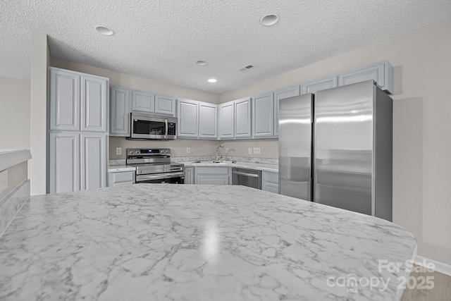 kitchen featuring stainless steel appliances, recessed lighting, visible vents, gray cabinetry, and a sink