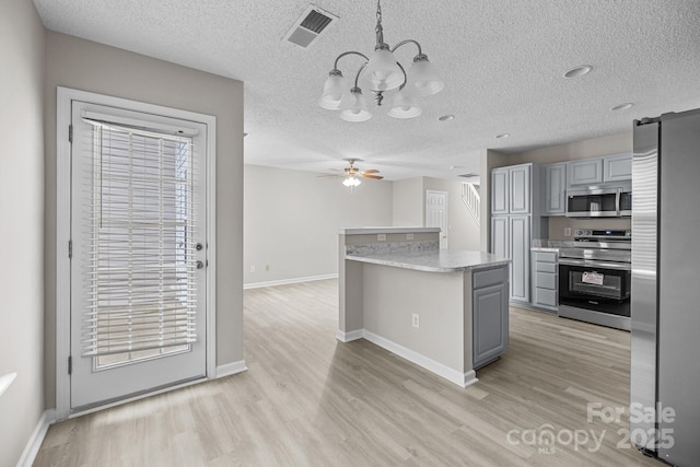 kitchen with visible vents, light wood-style flooring, decorative light fixtures, stainless steel appliances, and gray cabinetry