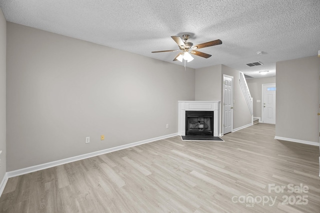 unfurnished living room featuring baseboards, a fireplace with flush hearth, visible vents, and light wood-style floors