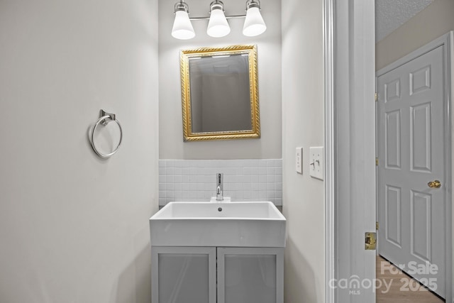 bathroom with tile walls, a wainscoted wall, vanity, and a textured ceiling