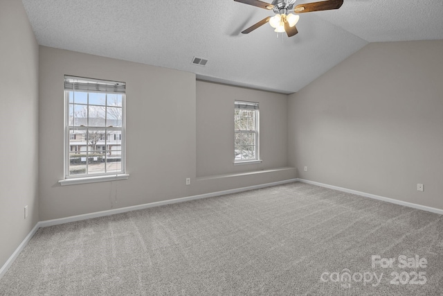 spare room with lofted ceiling, visible vents, light carpet, a textured ceiling, and baseboards