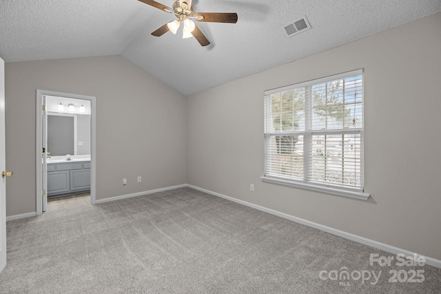 unfurnished bedroom featuring lofted ceiling, light colored carpet, visible vents, a textured ceiling, and baseboards