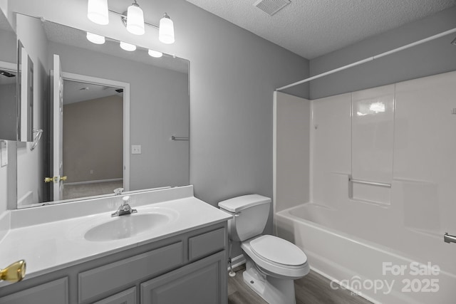 full bathroom with visible vents, toilet, a textured ceiling, vanity, and  shower combination