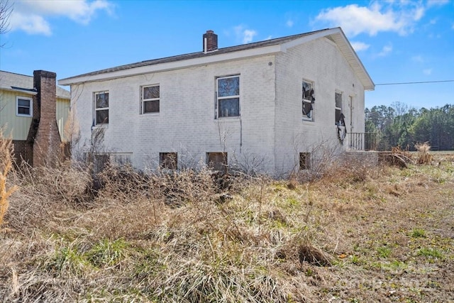 view of side of home featuring a chimney and brick siding