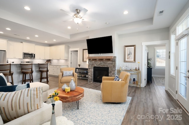 living room featuring a fireplace, dark wood-type flooring, and ceiling fan