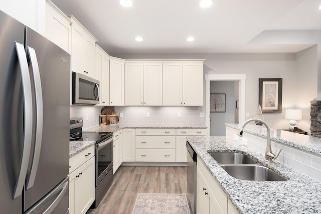 kitchen featuring sink, stainless steel appliances, white cabinets, and light stone counters