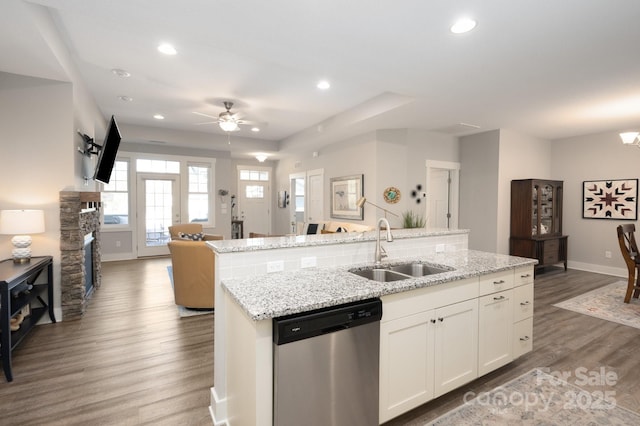 kitchen featuring an island with sink, sink, stainless steel dishwasher, wood-type flooring, and white cabinets