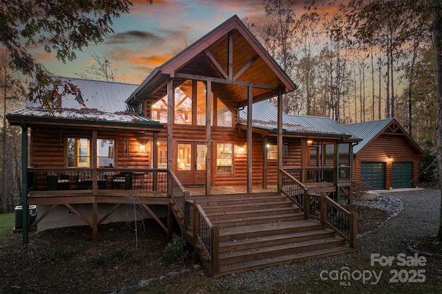 back house at dusk with covered porch, central AC unit, and a garage