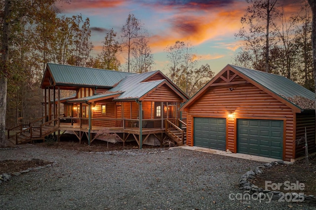 log-style house featuring covered porch, an outdoor structure, and a garage