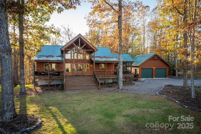 log home featuring covered porch, a front lawn, a garage, and an outbuilding