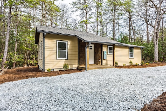 view of front facade featuring gravel driveway and roof with shingles