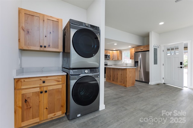 washroom with a sink, stacked washer and dryer, laundry area, and wood finished floors