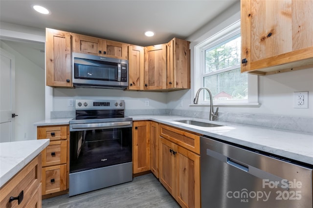 kitchen with light wood-style flooring, recessed lighting, a sink, light countertops, and appliances with stainless steel finishes