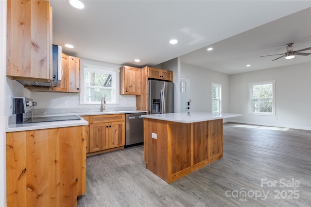 kitchen with appliances with stainless steel finishes, a center island, open floor plan, and light countertops