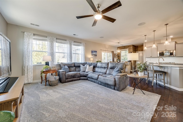 living room featuring plenty of natural light, dark wood finished floors, and visible vents