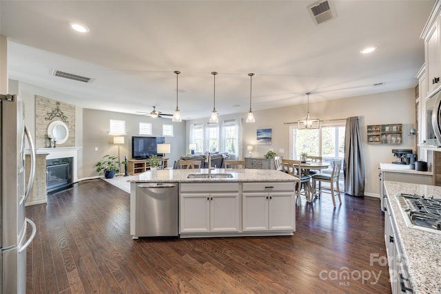 kitchen featuring a premium fireplace, a sink, white cabinetry, open floor plan, and appliances with stainless steel finishes