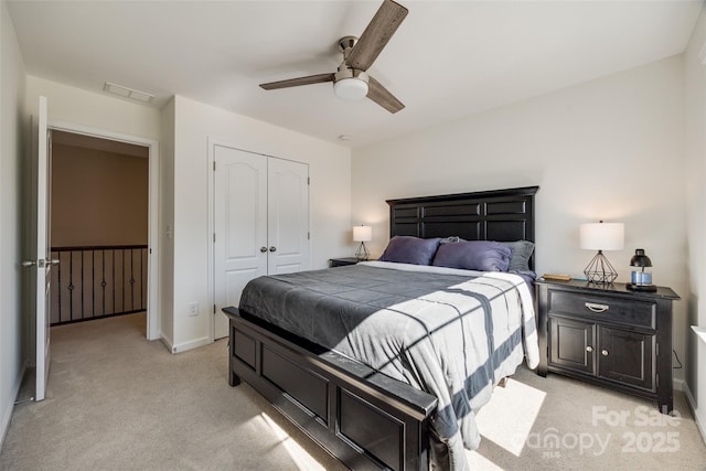 bedroom with a closet, visible vents, light carpet, ceiling fan, and baseboards