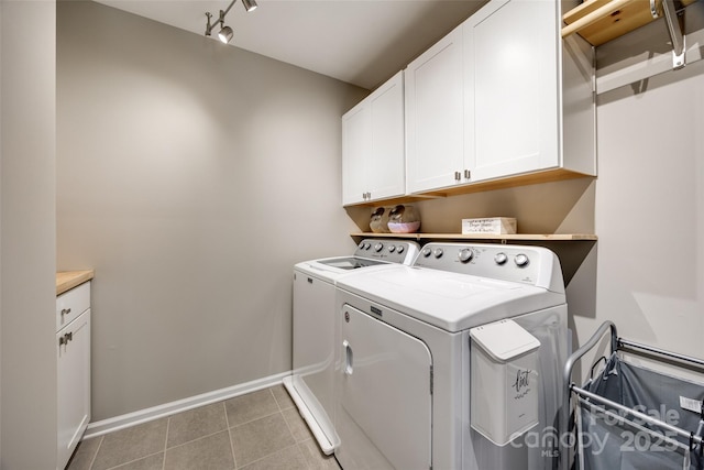 clothes washing area featuring cabinet space, light tile patterned floors, baseboards, and washer and clothes dryer