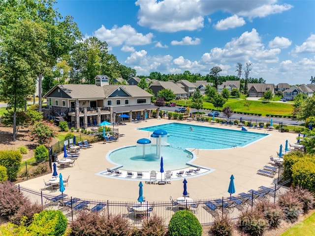 community pool with a residential view, a patio area, and fence