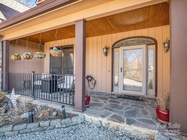 property entrance with covered porch and roof with shingles