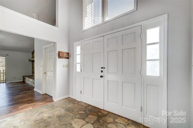 foyer entrance with stone finish flooring, baseboards, and a wealth of natural light