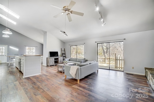 living room with dark wood-type flooring, a skylight, baseboards, and a ceiling fan