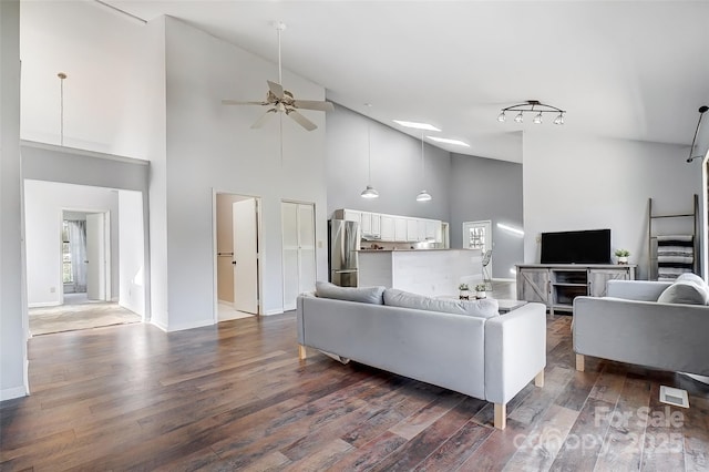 living area featuring dark wood-style floors, ceiling fan, high vaulted ceiling, and baseboards