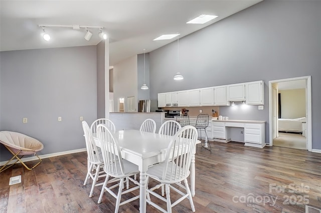 dining space with high vaulted ceiling, a skylight, baseboards, and dark wood-style flooring