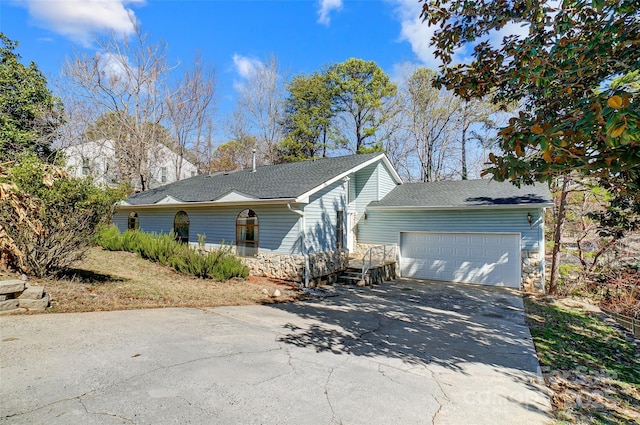 view of front of home featuring a garage, concrete driveway, a shingled roof, and stone siding