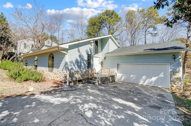 view of front of property featuring an attached garage, stone siding, and concrete driveway