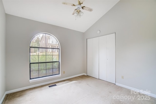 unfurnished bedroom with baseboards, visible vents, carpet, vaulted ceiling, and a closet