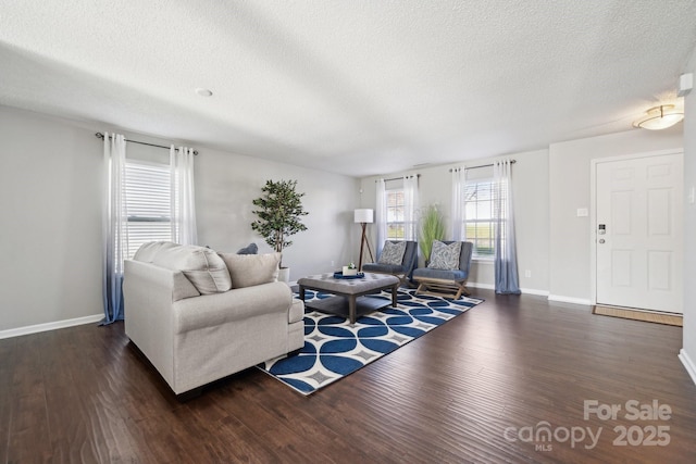 living room featuring a textured ceiling, baseboards, and wood finished floors