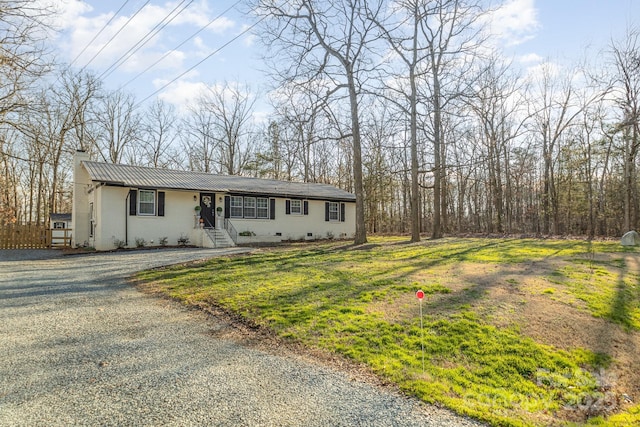 view of front of property featuring a chimney, a front yard, crawl space, metal roof, and driveway