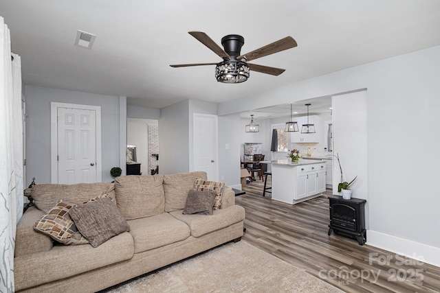 living room with visible vents, ceiling fan, baseboards, and wood finished floors